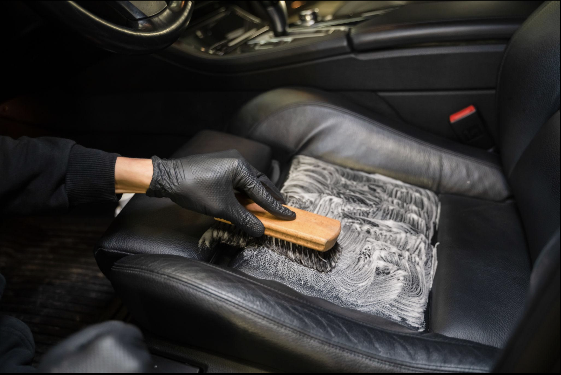 Deep cleaning a leather car seat with foam and brush